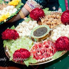 several trays filled with food and flowers on top of each other in front of people