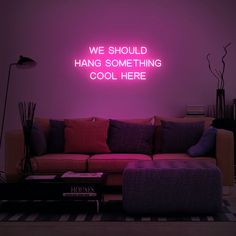 a living room filled with furniture and a neon sign on the wall that says we should hang something cool here