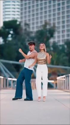 a man and woman are dancing on the sidewalk in front of tall buildings with their arms around each other