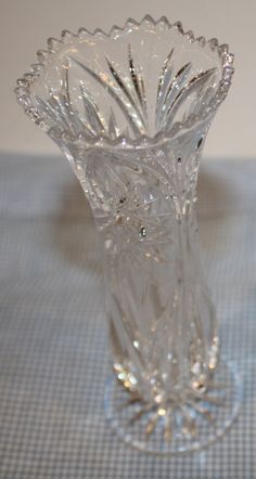 a clear glass vase sitting on top of a blue and white tablecloth covered table