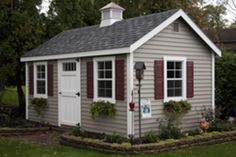 a small gray shed with red shutters and windows