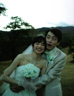 a bride and groom posing for a photo in front of the camera on their wedding day