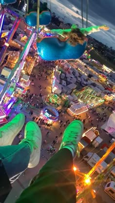 someone is hanging upside down at an amusement park with their feet in the air above them