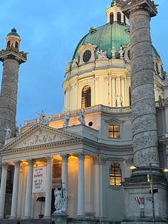 an old building with columns and a dome on top at dusk, lit up by street lights