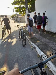 a group of people standing on the side of a road next to a bike and another person holding an umbrella