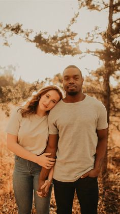 a man and woman standing next to each other in front of some trees with the sun shining on them