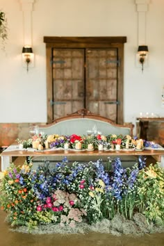 an arrangement of flowers and candles on a table in front of a wooden door at a wedding