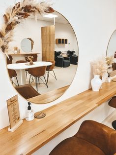 a mirror that is on the side of a wall next to a table and chairs