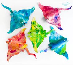 four different colored fish are shown in the shape of watercolors on a white background