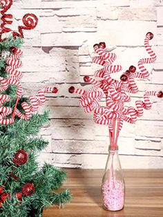 a vase filled with candy canes next to a small christmas tree on a table