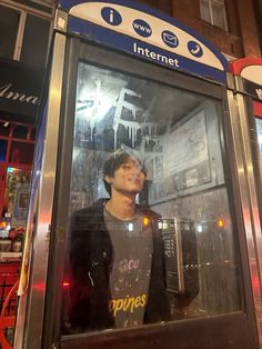 a young man standing in front of a phone booth