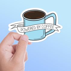 a hand holding up a sticker with the words powered by coffee in front of it