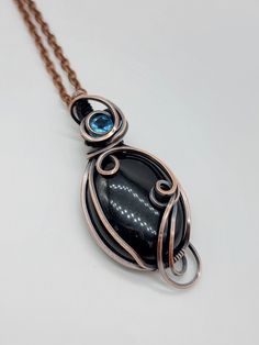 Opaque black obsidian oval cabochon with a nice little blue topaz facet... made with copper and comes on an 18 inch copper chain. See photos for pic of chain... Comes in a gift box ready to wear Unique Black Oval Pendant Necklace, Oval Copper Necklace For Gift, Black Copper Pendant Jewelry, Unique Black Cabochon Necklace, Black Copper Wire Pendant Necklaces, Black Round Copper Jewelry, Black Copper Round Jewelry, Black Hand Forged Jewelry For Gift, Hand Forged Black Jewelry For Gift