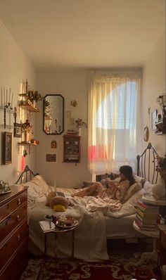 a woman laying in bed with her feet up on the end table next to an open window