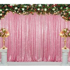 a pink backdrop with flowers and gold vases in front of the curtain for a wedding ceremony