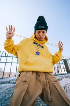 a young man in a yellow hoodie and khaki pants