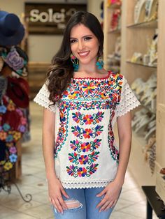 This beautiful blouse is made with a traditional Mexican floral embroidery. The blouse is full of colorful embroidered flowers. The neck has details made by hand with crochet. This Beautiful Floral Otomi blouse is the perfect addition to your wardrobe. It's lightweight, handmade out of fine Mexican cotton and is embroidered by Artisanal Machine in Puebla, Mexico. The Jewelry modeled you can find here: https://www.etsy.com/es/listing/1095300390/arete-artesanal-mexicano-aretes?click_key=0cf811c97b Mexican Blouses Embroidery, Mexican Dresses For Women Embroidery Blouses, Traditional Embroidered Crew Neck Top For Spring, Traditional Crew Neck Embroidered Top For Spring, Festive White Top With Embroidered Sleeves, Traditional Multicolor Short Sleeve Tops, Casual Multicolor Tops With Embroidered Sleeves, Traditional Short Sleeve Top With Multicolor Embroidery, Multicolor Embroidered Short Sleeve Blouse