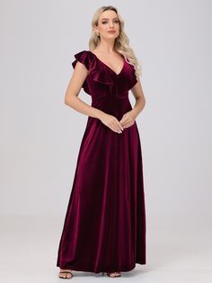 a woman wearing a long velvet dress with ruffled sleeves and a v neckline