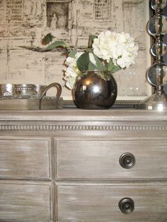 a vase with flowers sitting on top of a dresser