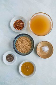 bowls filled with different types of food on top of a white countertop next to two cups