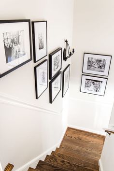 a staircase with pictures on the wall and wood flooring in front of it's handrails