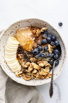 a bowl filled with granola, bananas and blueberries on top of a table