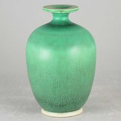 a green vase sitting on top of a white table