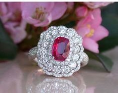 a close up of a ring on a table with flowers in the background and pink flowers behind it