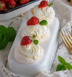 two desserts with strawberries are on a white plate next to a silver fork