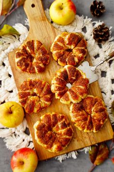 apple pies on a cutting board with apples and pine cones in the back ground