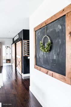 a chalkboard with a wreath hanging on it's side next to a wooden door