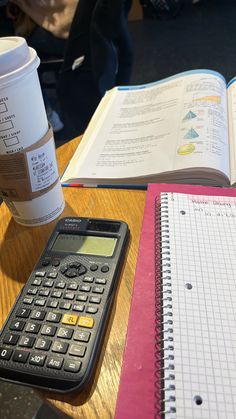 a calculator sitting on top of a wooden table next to a cup of coffee