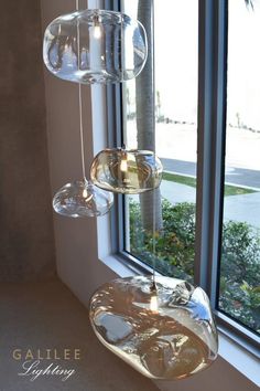 three hanging glass bowls in front of a window