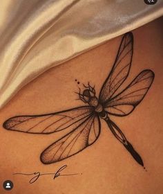 a black and white photo of a dragonfly on the back of a woman's stomach