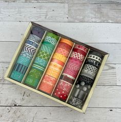 a box filled with lots of different types of washi tapes on top of a wooden table