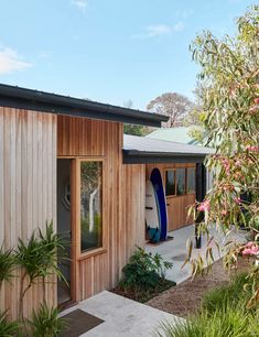 there is a surfboard leaning against the side of this house in front of some trees