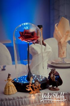 the beauty and the beast figurines are under a glass clochet dome