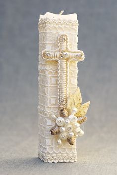 a white candle with pearls and a cross on it