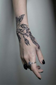 a woman's hand with a black and white flower tattoo on her left arm