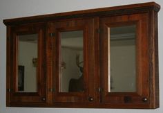 a wooden cabinet with two mirrors on the front and one door open to show a deer's head