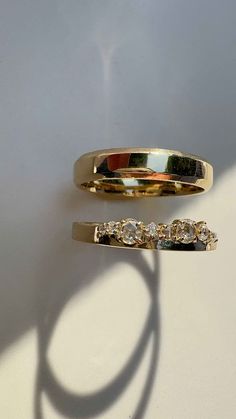 two gold wedding bands with three diamonds on each side, set against a white background