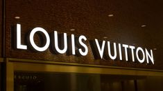 the sign for louis vuitton is lit up on the side of a building