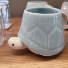 a ceramic turtle mug sitting on top of a table next to other glass cups and containers