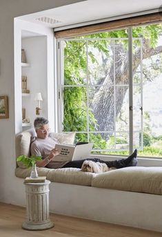 an older man sitting on a couch with his laptop computer in front of him, looking out the window