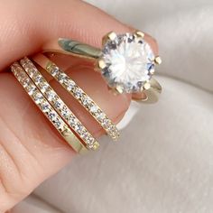 a person's hand holding three rings with a diamond in the middle and two on each side