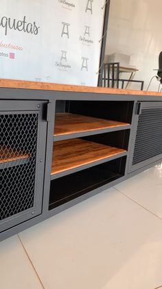 a large entertainment center with wooden shelves and metal mesh doors on the front, in a room with white tile flooring