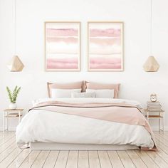 two paintings on the wall above a bed in a white room with wood flooring