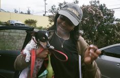 a woman is holding a small dog in her lap while standing next to a car