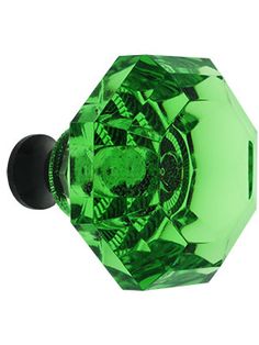 a green glass door knob with a gold top on a white background and an image of a diamond in the middle