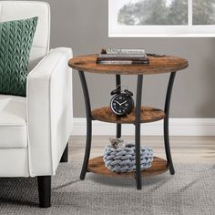 an end table with a clock on it in front of a white couch and window